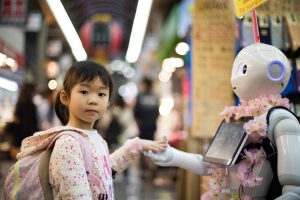 Nena asiàtica saludant un robot.