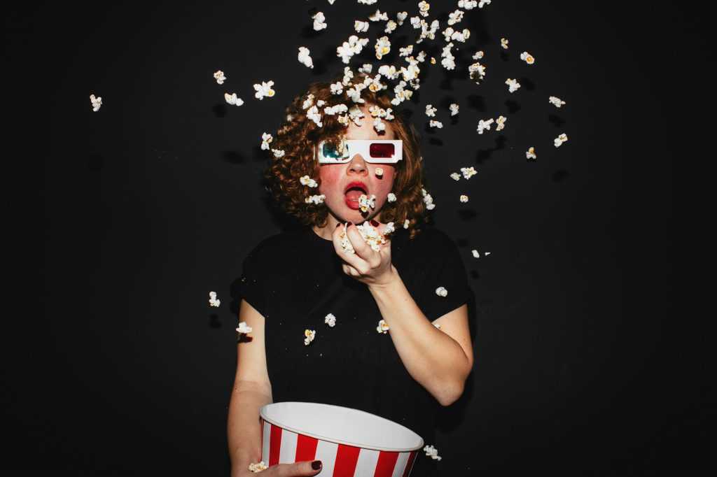 Portrait of a cute girl eating popcorn, wearing 3d glasses
