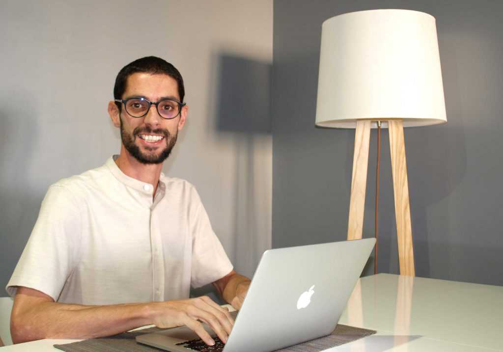 Fotografía de Oroitz, graduado del máster sonriendo delante del ordenador