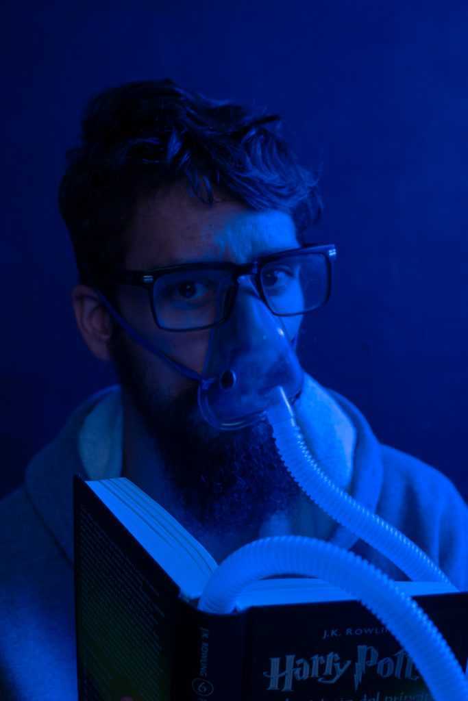 Hombre con mascarilla de oxigeno conectado a un libro.