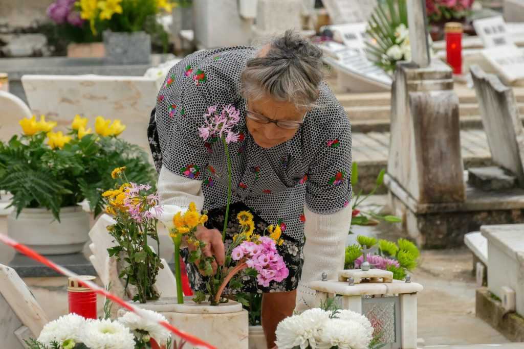 Mujer en cementerio arreglando flores